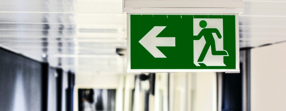 Green fire exit sign attached to ceiling